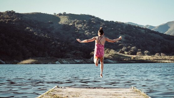 Man sieht ein Mädchen wie es in einen See springt